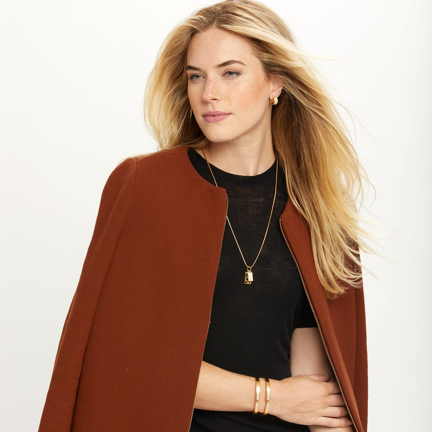 Model wearing a Brighton gold-plated pendant necklace with dual charms and coordinating Brighton accessories including hoop earrings