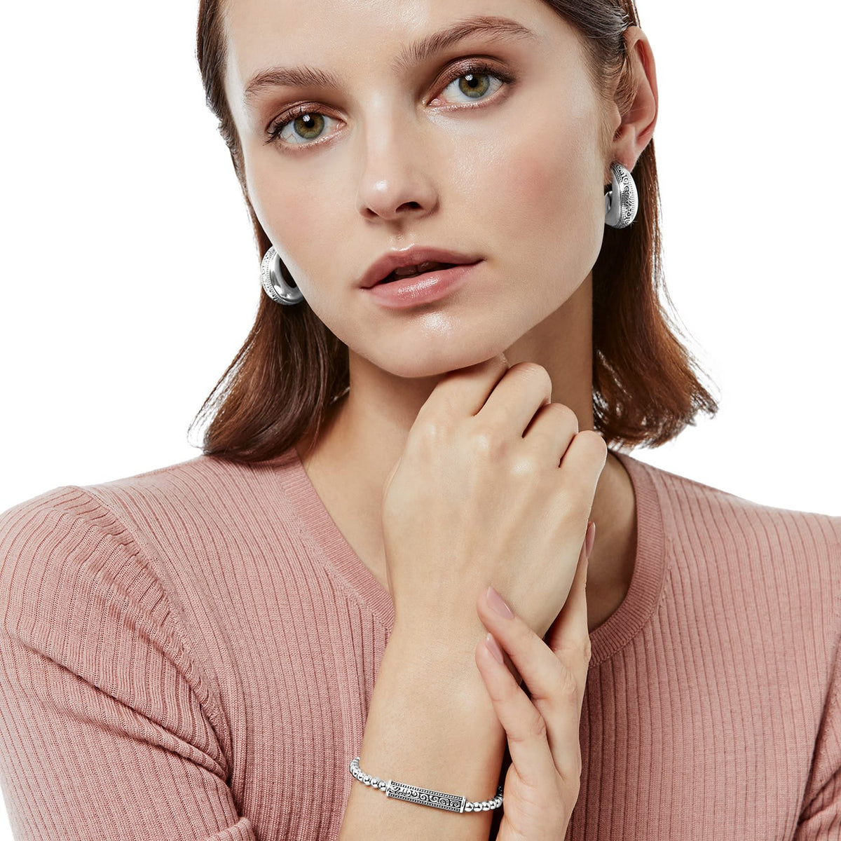 Model wearing Brighton silver-plated hoop earrings with engraved scroll detail paired with a matching beaded link bracelet