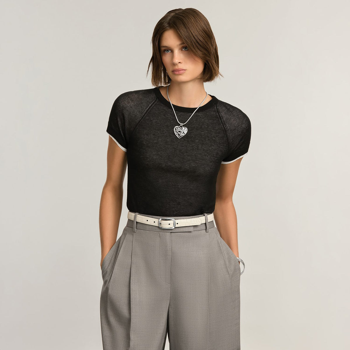 Model wearing a Brighton silver heart pendant necklace on a snake chain with ornate scrollwork design