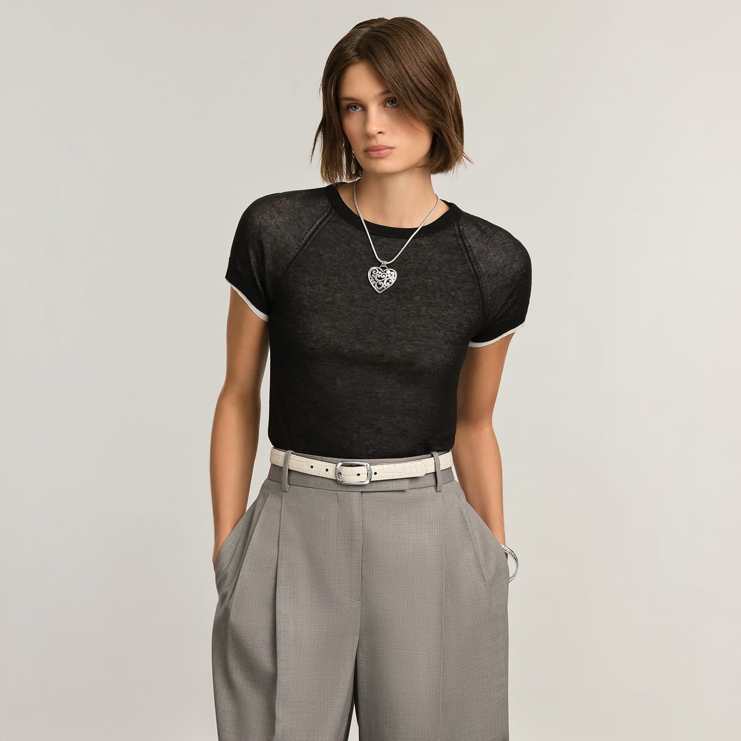 Model wearing a Brighton silver heart pendant necklace on a snake chain with ornate scrollwork design