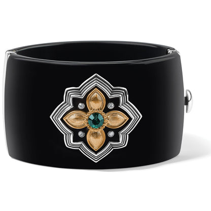 Brighton black hinged cuff bracelet with two-tone floral medallion, green crystal center, and clear crystals on a white background