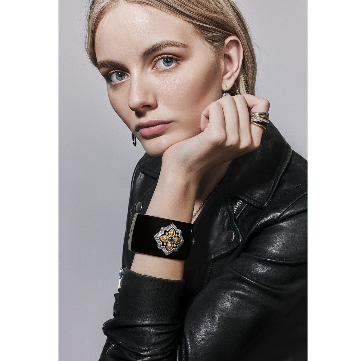 Model wearing a Brighton black cuff bracelet with two-tone floral medallion and green crystal center accent