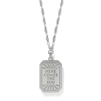 Brighton pendant necklace with rectangular silver-tone tag engraved Here Comes The Sun and beaded chain on a white background
