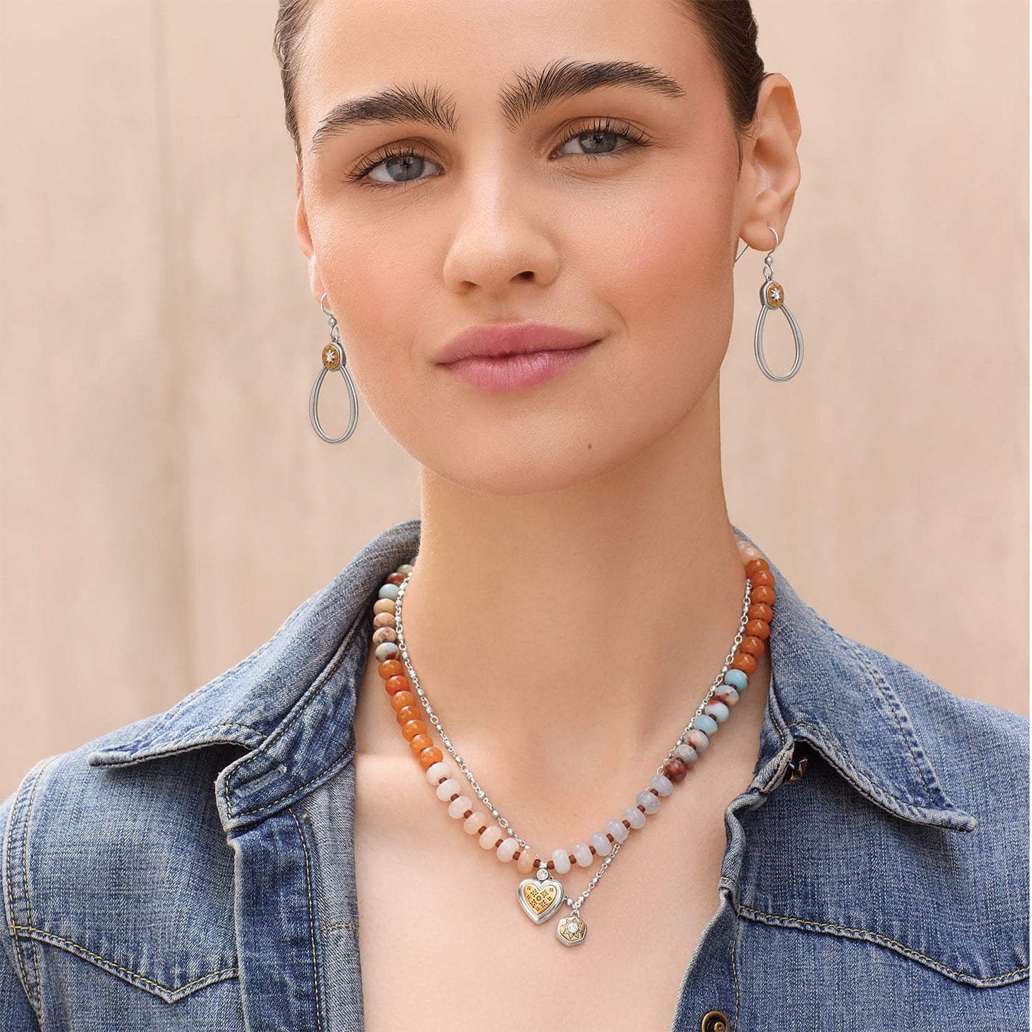 Model wearing Brighton two-tone drop earrings with crystal accents and coordinating Brighton beaded necklaces with heart pendant