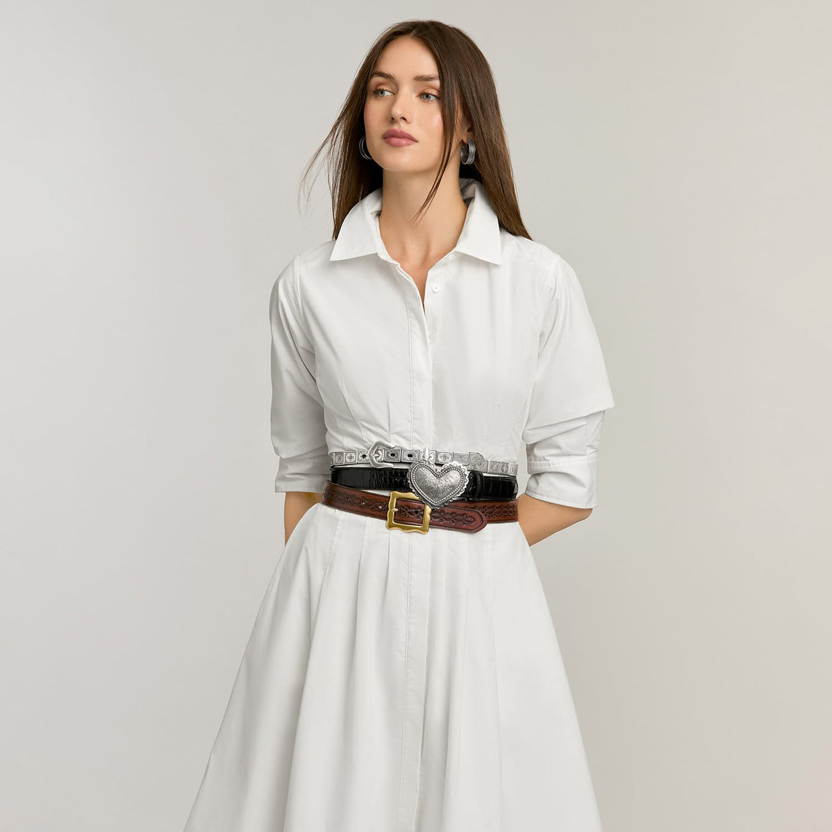 Model wearing Brighton leather belts stacked at the waist with silver studded, black croc, and brown buckle designs