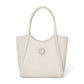 Brighton tote handbag in cream leather with woven side panels, circular medallion emblem, and dual top handles on a white background