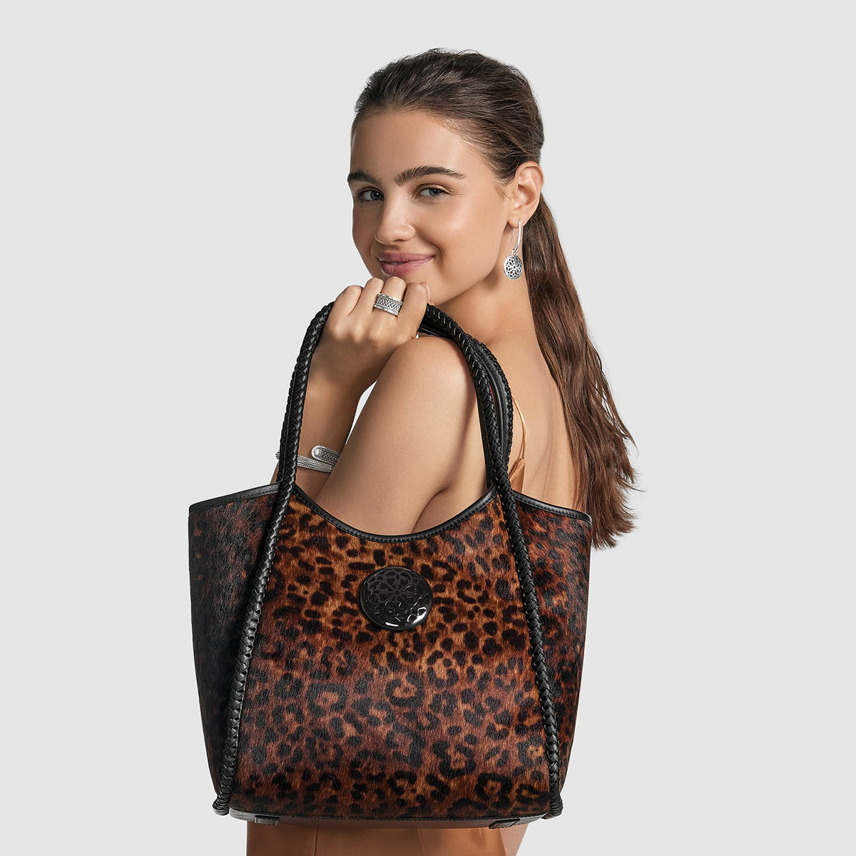 Model with a Brighton leopard print tote handbag featuring braided black leather straps and circular black medallion accent