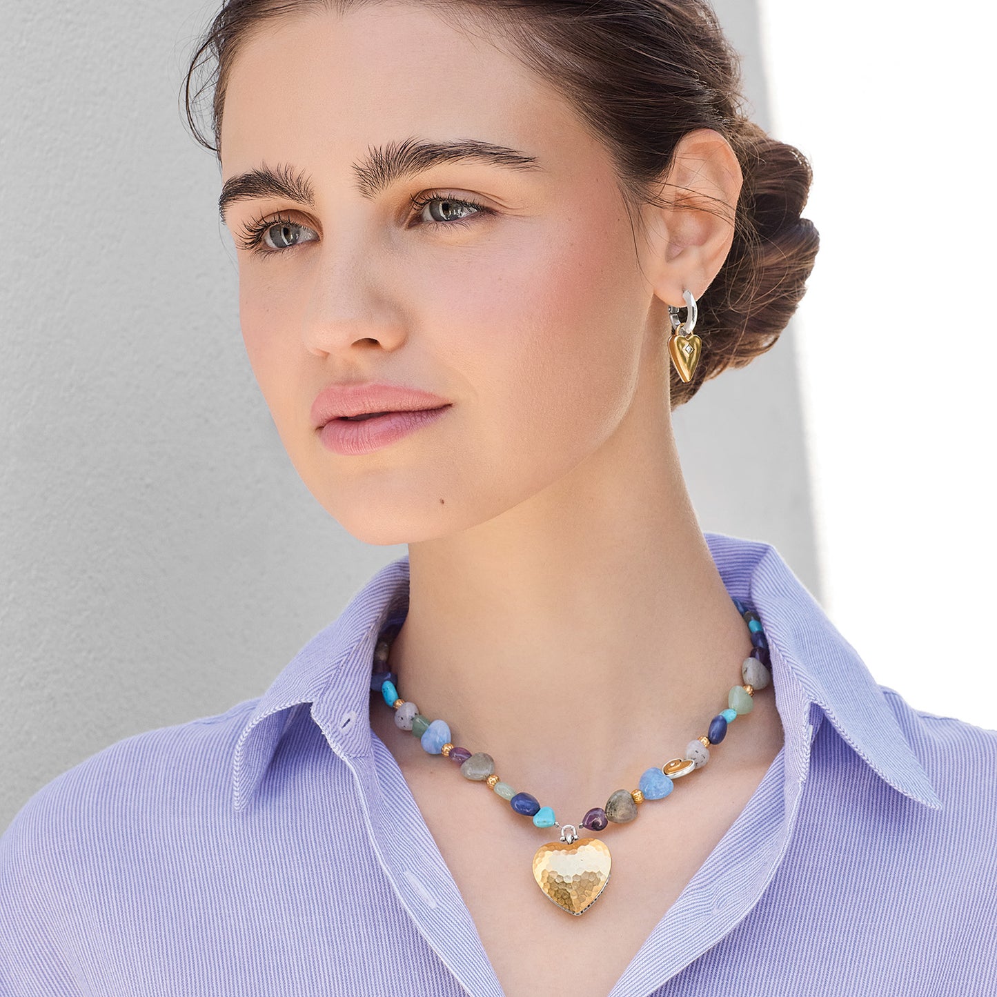 Model wearing a Brighton beaded necklace with multicolor stones and gold-plated hammered heart pendant, paired with heart earrings