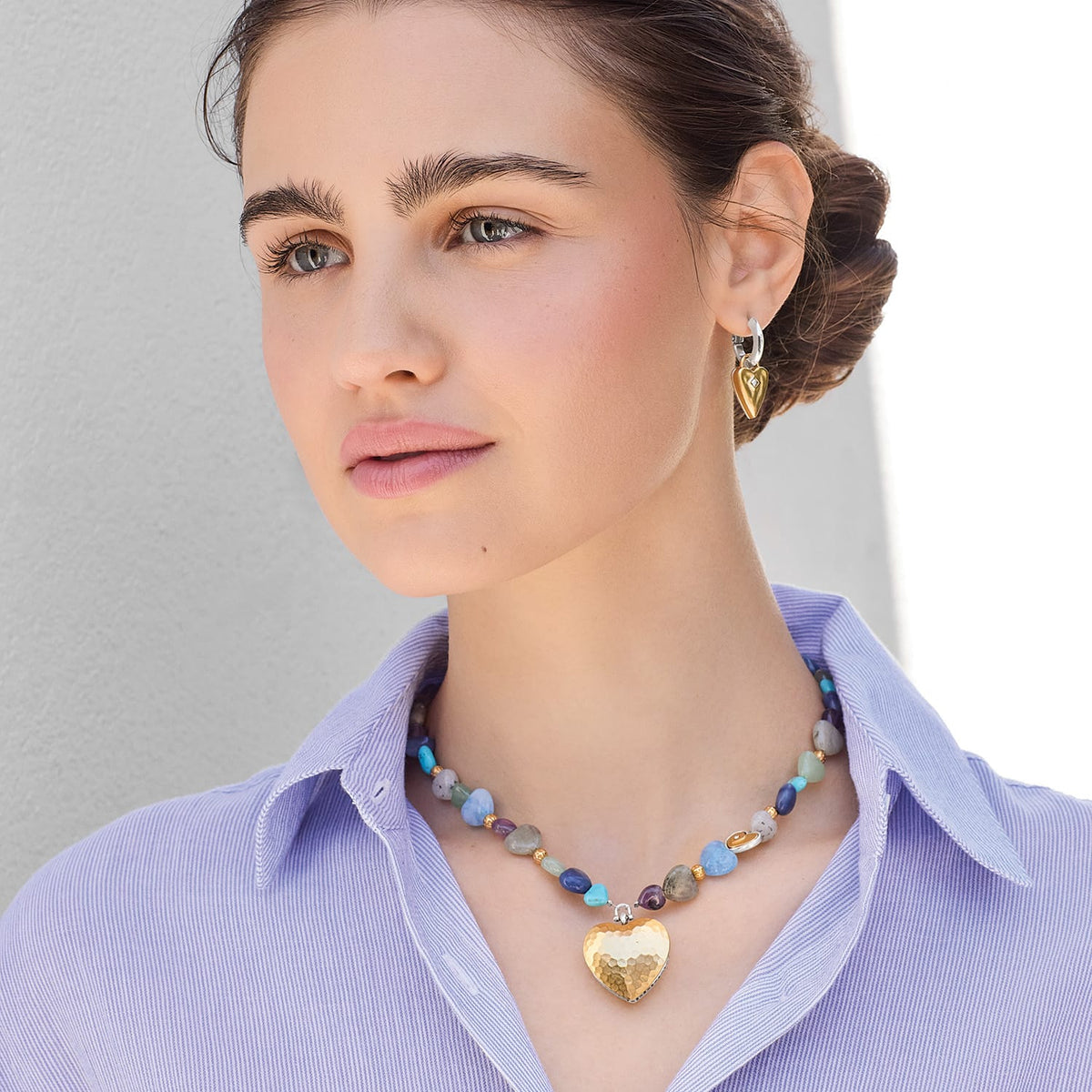 Model wearing a Brighton beaded gemstone necklace with hammered gold heart pendant paired with gold heart hoop earrings