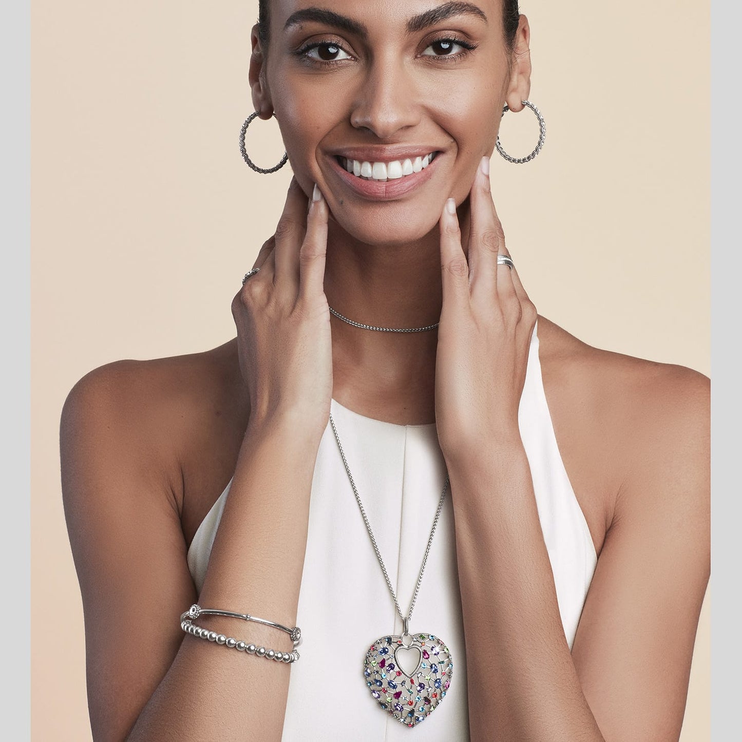 Model wearing a Brighton silver-plated heart pendant necklace with multicolored crystals and coordinating Brighton accessories