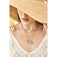 Model wearing layered Brighton silver-plated necklaces with pearl bar, seashell, and conch shell pendants