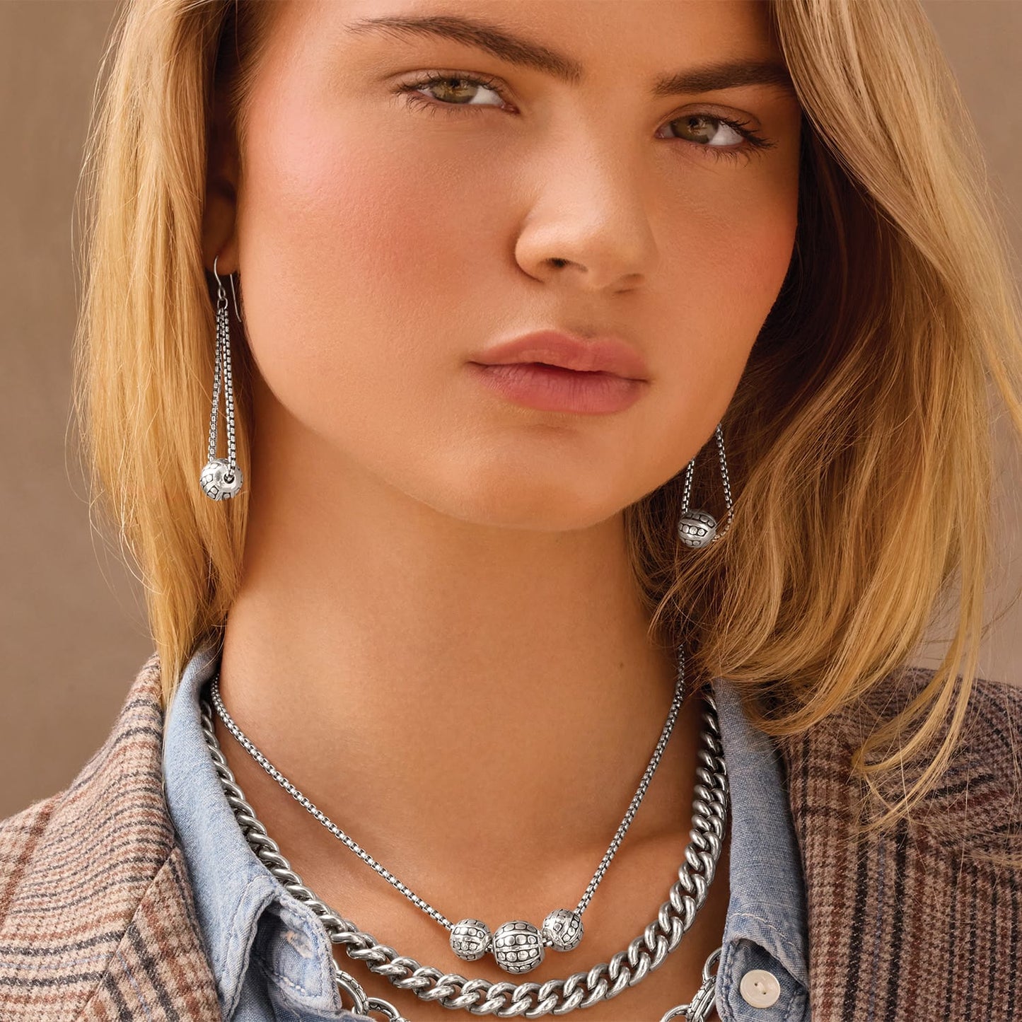 Model wearing Brighton silver-plated drop earrings with patterned beads paired with layered chain necklaces featuring beaded accents