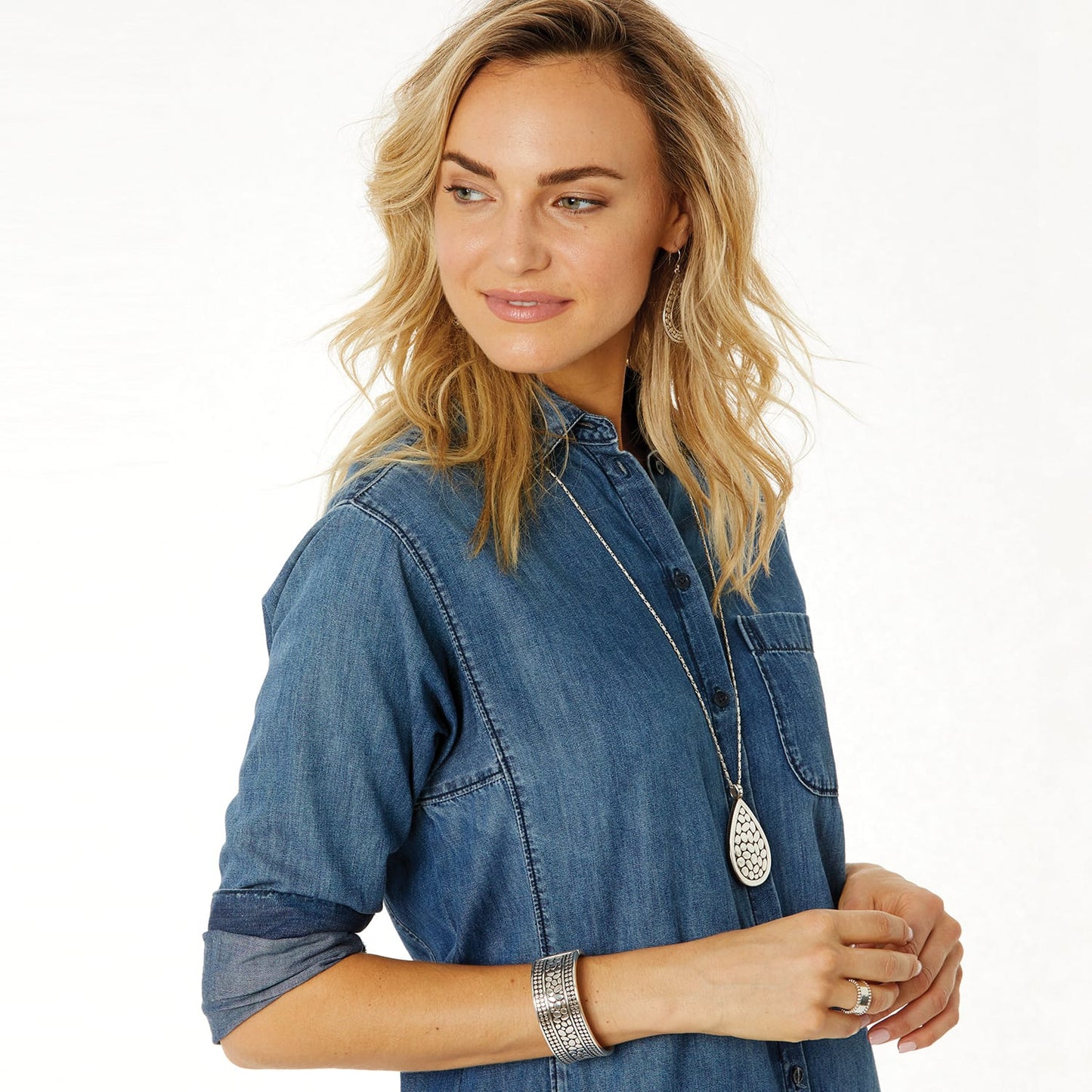 Model wearing a Brighton silver-plated teardrop pendant necklace with coordinating silver-plated earrings and textured cuff bracelet