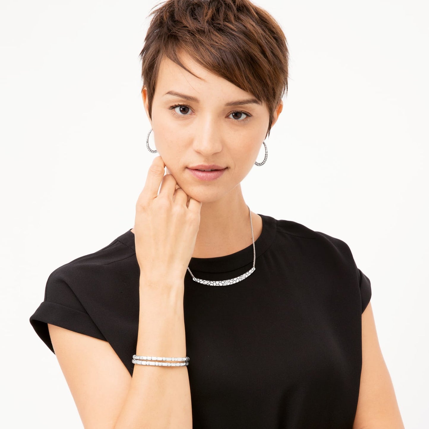 Model wearing a Brighton silver-tone pebbled bar necklace paired with matching hoop earrings and stacked bracelets