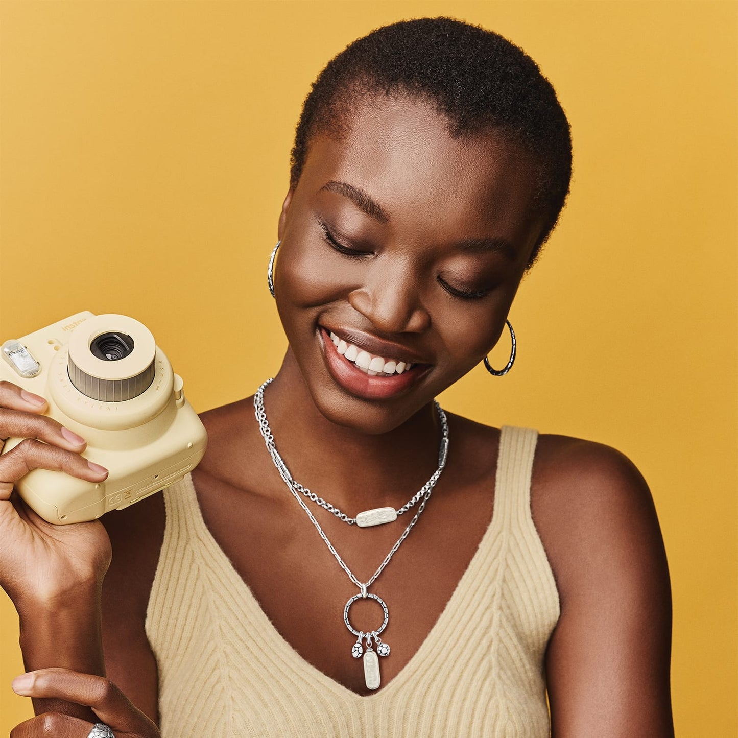 Model wearing Brighton silver-plated layered necklaces with oval pendant and circle charm, paired with silver-plated hoop earrings