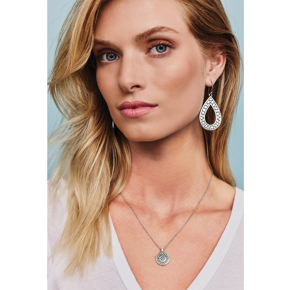 Model wearing Brighton silver-plated teardrop earrings with dotted texture paired with a matching round pendant necklace