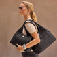 Model with a Brighton black quilted heart-pattern tote handbag, styled with Brighton silver hoop earrings and watch