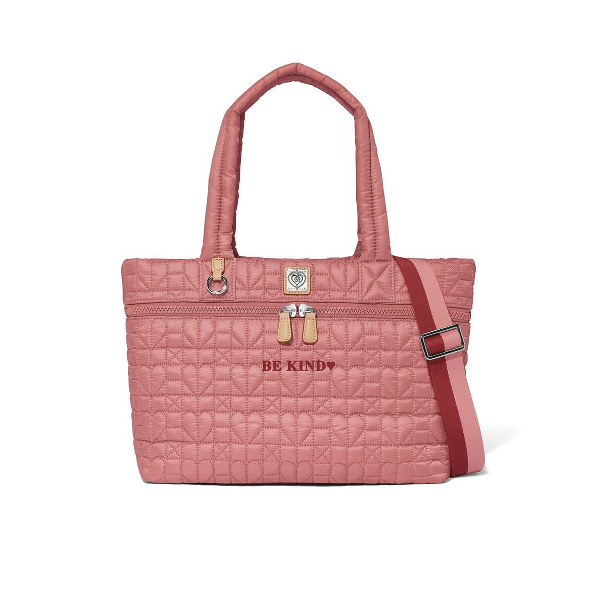 Brighton quilted tote handbag in pink with heart pattern, Be Kind embroidery, and striped crossbody strap on a white background