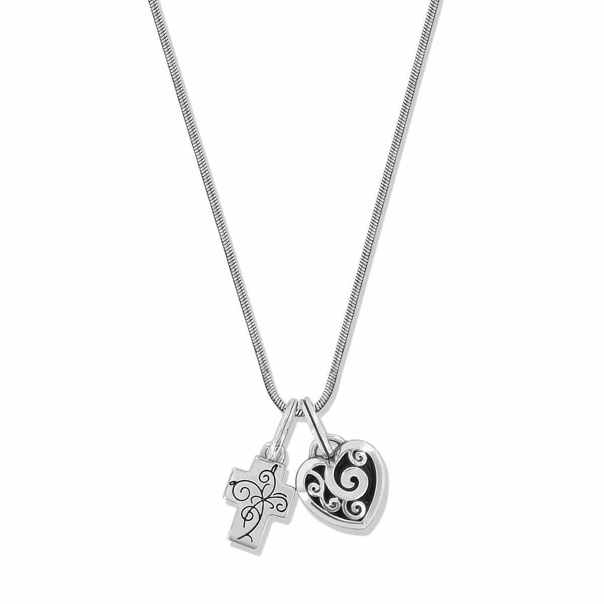 Brighton pendant necklace with silver-plated cross and heart charms featuring scroll detailing on a white background