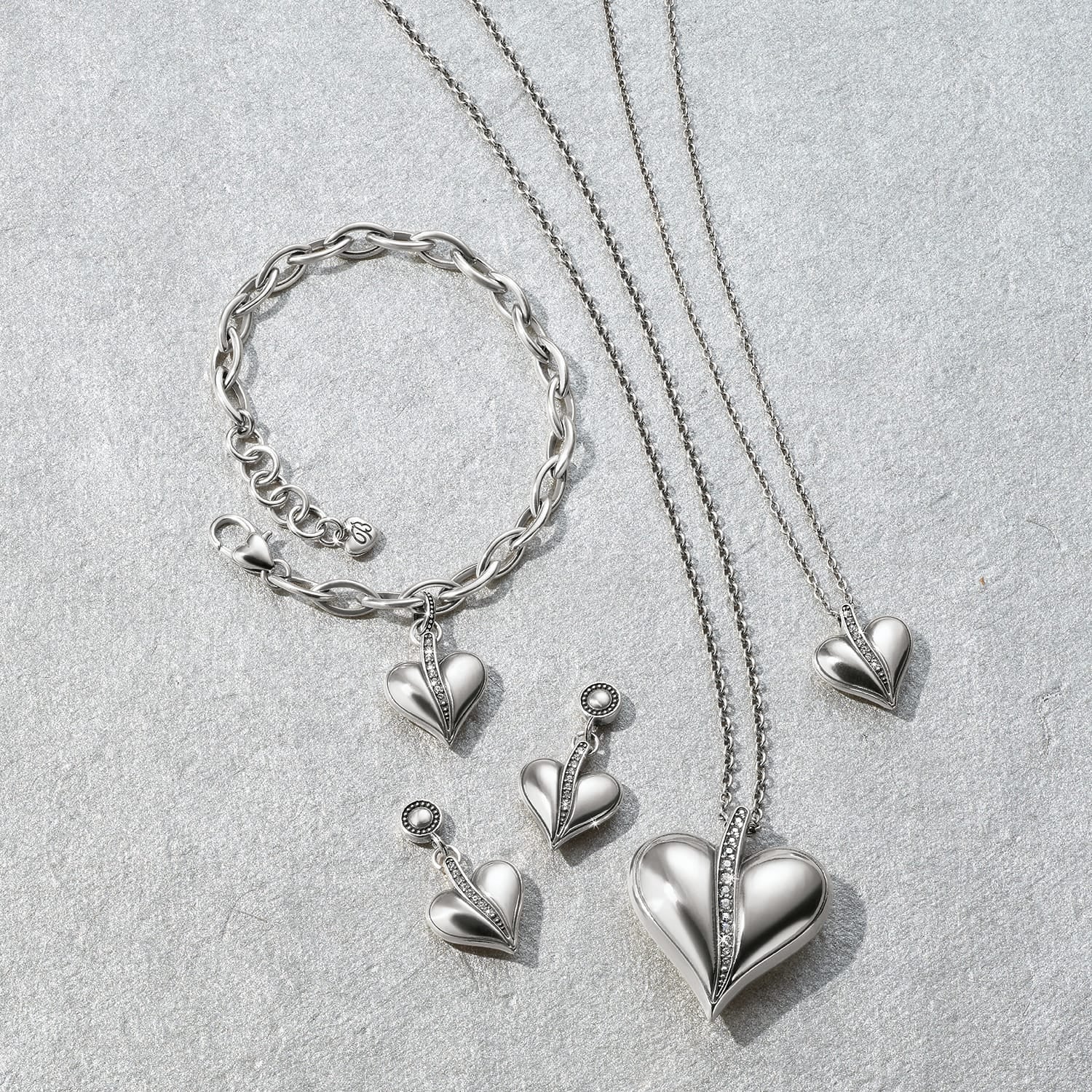 Brighton silver-plated heart jewelry set styled with chain bracelet and coordinating necklaces featuring crystal accents on gray stone
