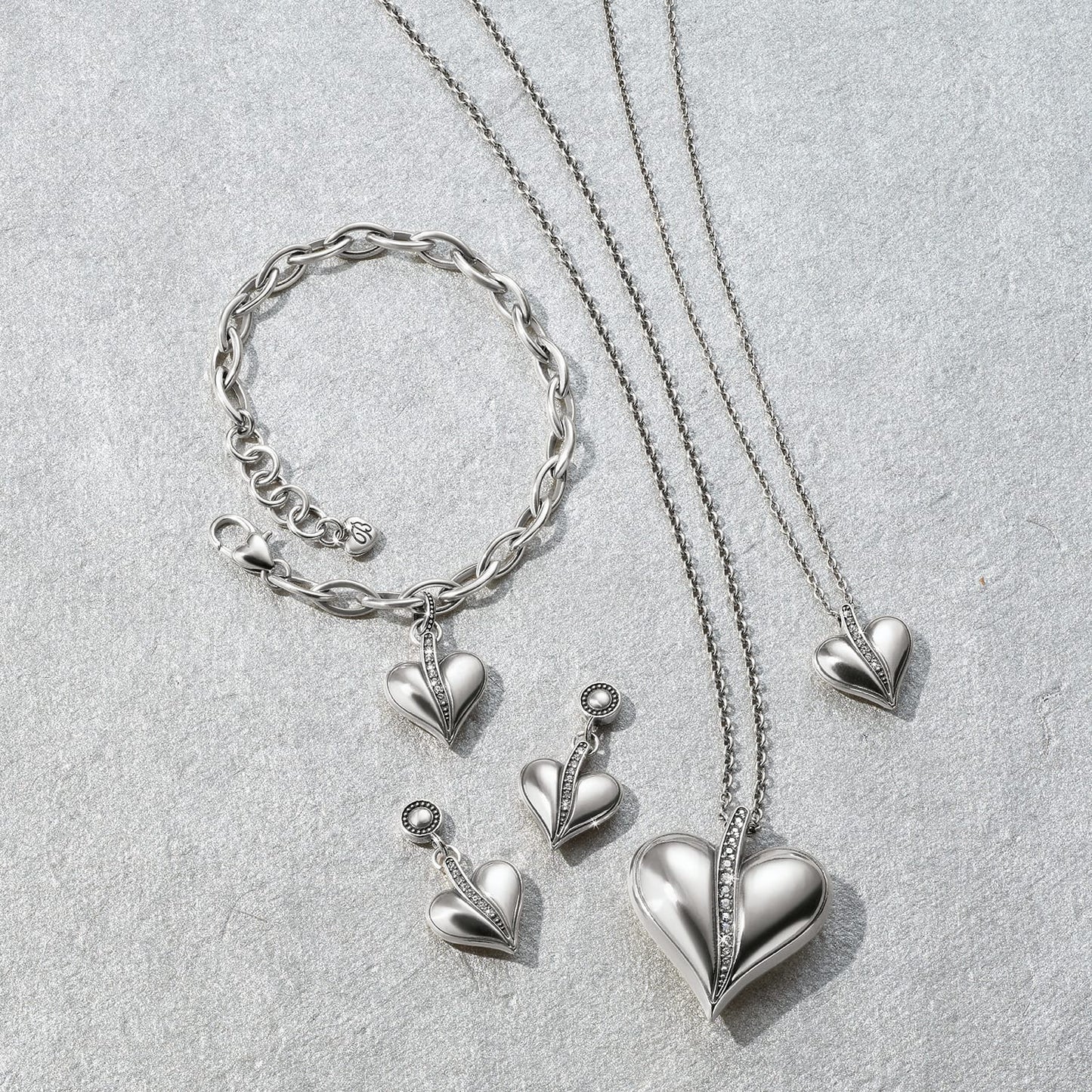 Brighton silver-plated heart jewelry set styled with chain bracelet and coordinating necklaces featuring crystal accents on gray stone
