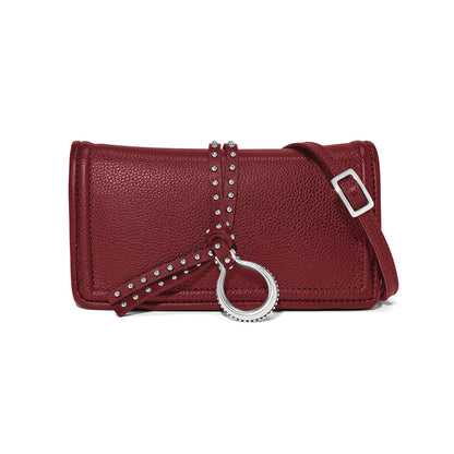 Brighton crossbody handbag in burgundy pebbled leather with studded strap, silver-tone ring accent, and adjustable strap on a white background