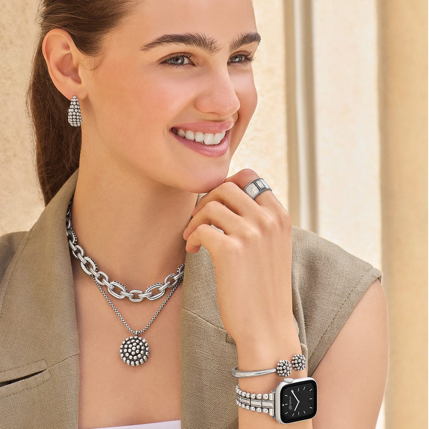 Model wearing Brighton silver-plated beaded hoop earrings with layered chain necklace, pendant, ring, and watch bracelet