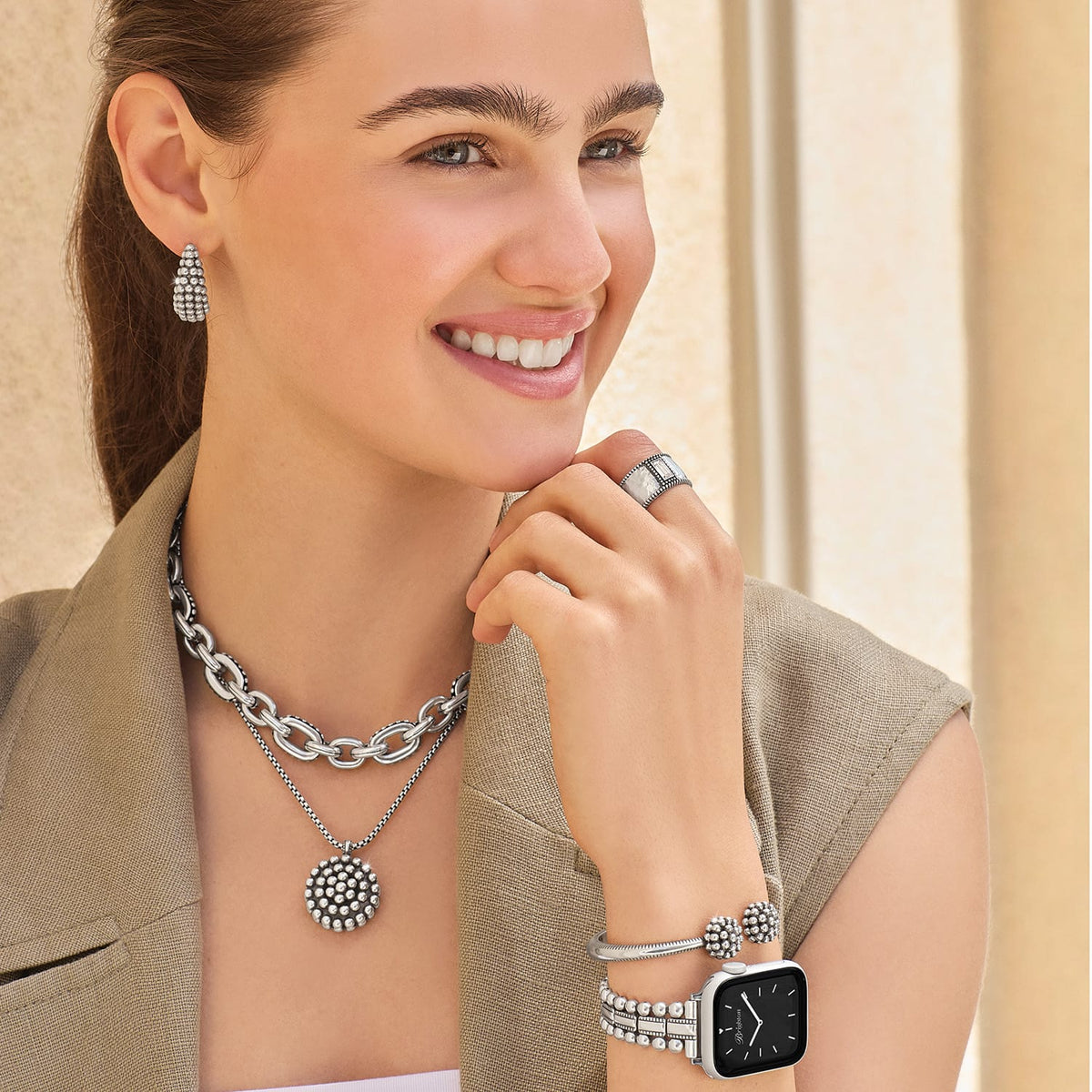 Model wearing Brighton silver-plated beaded hoop earrings with chunky chain necklace, medallion pendant, ring, bracelet, and watch