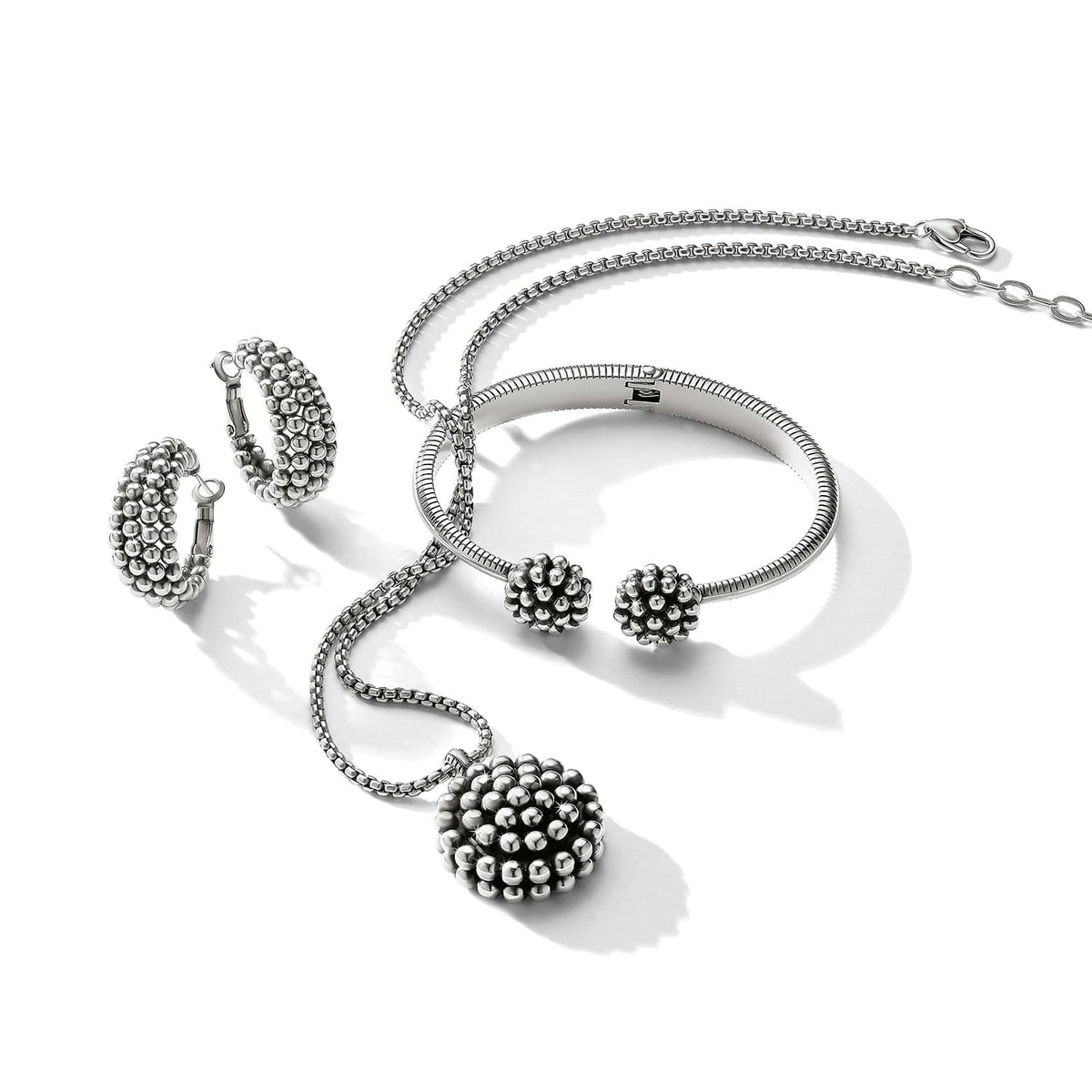 Brighton silver-plated jewelry set styled with beaded pendant necklace, hoop earrings, and matching cuff bracelet on white background