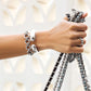 Pretty Tough Droplet Hinged Bangle worn by model with matching bracelet and handbag straps in her hand against a white background
