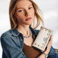 Model with a Brighton white leather wallet featuring gold and silver-tone studded accents and medallion detail