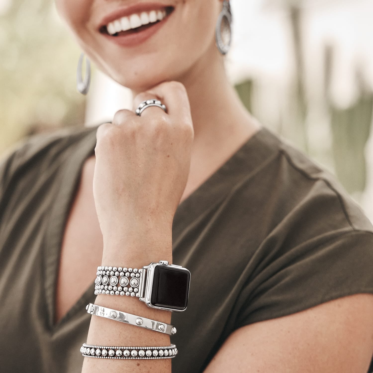 Model wearing a Brighton silver-plated beaded Apple watch band with coordinating Brighton bangles, ring, and hoop earrings