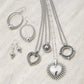 Brighton silver-plated jewelry set styled with hoop earrings, drop earrings, and heart pendant necklaces on stone background