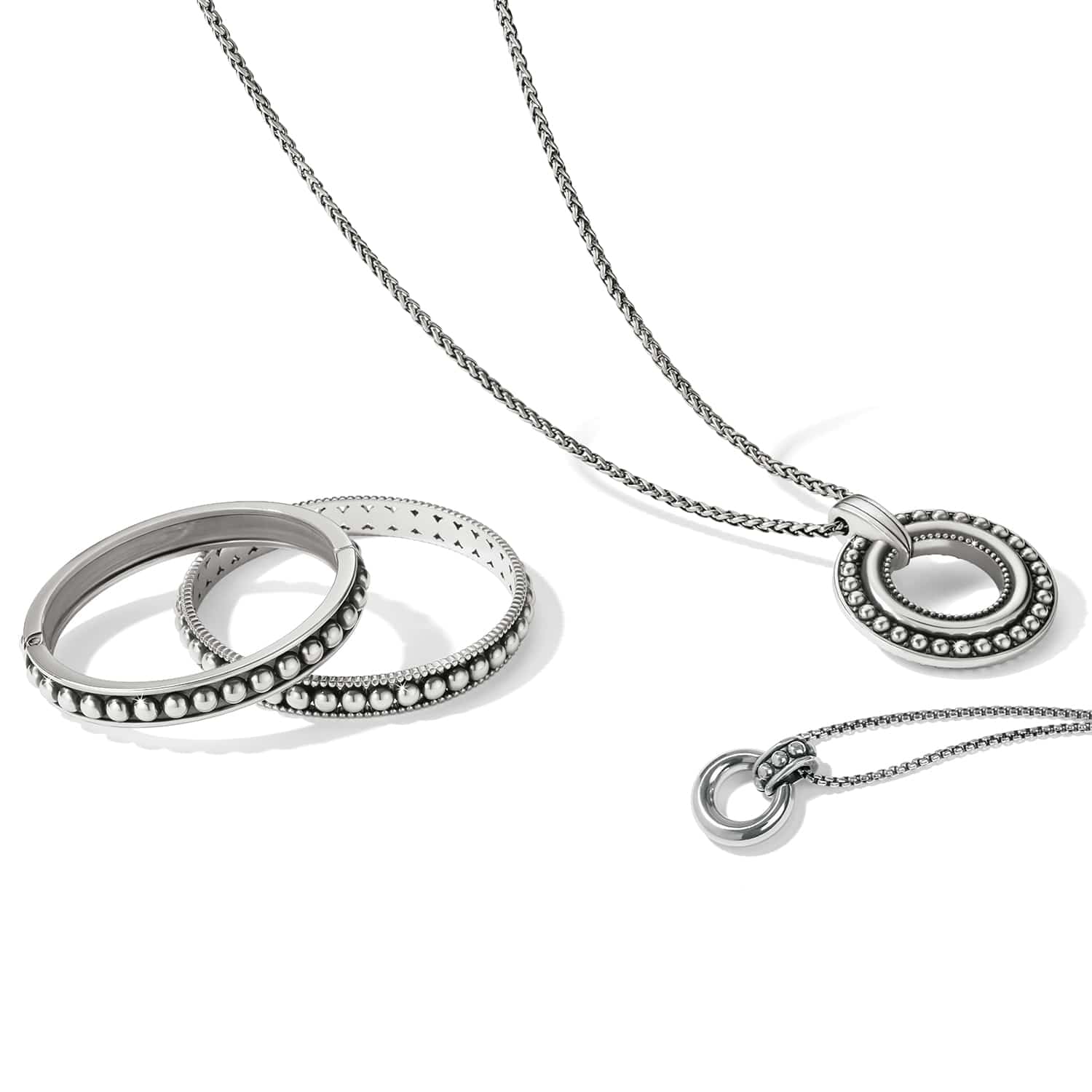Brighton silver-plated jewelry set styled with beaded bangles and circle pendant necklaces on a white background