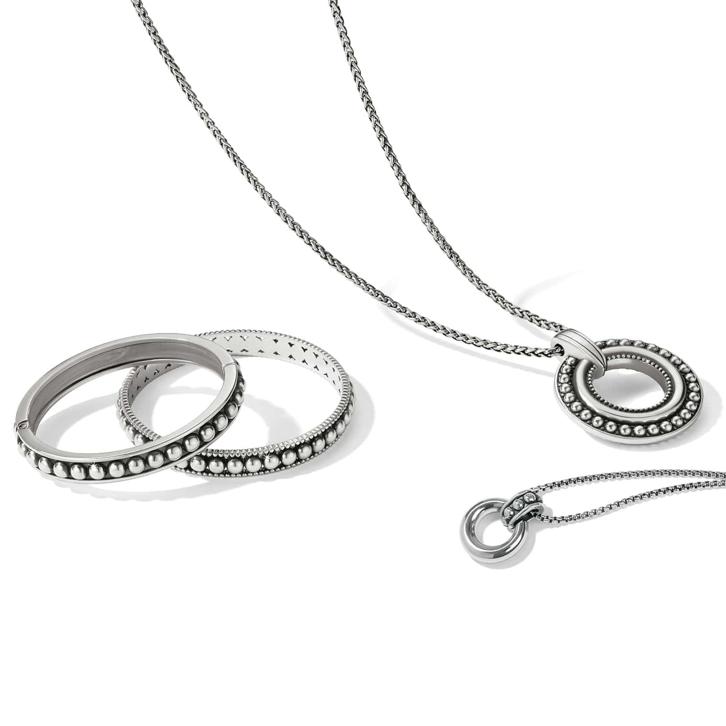 Brighton silver-plated jewelry set styled with beaded bangles and circle pendant necklaces on a white background