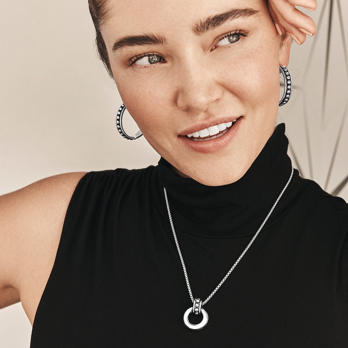 Model wearing Brighton silver-plated beaded hoop earrings paired with a silver-plated pendant necklace with crystal accents
