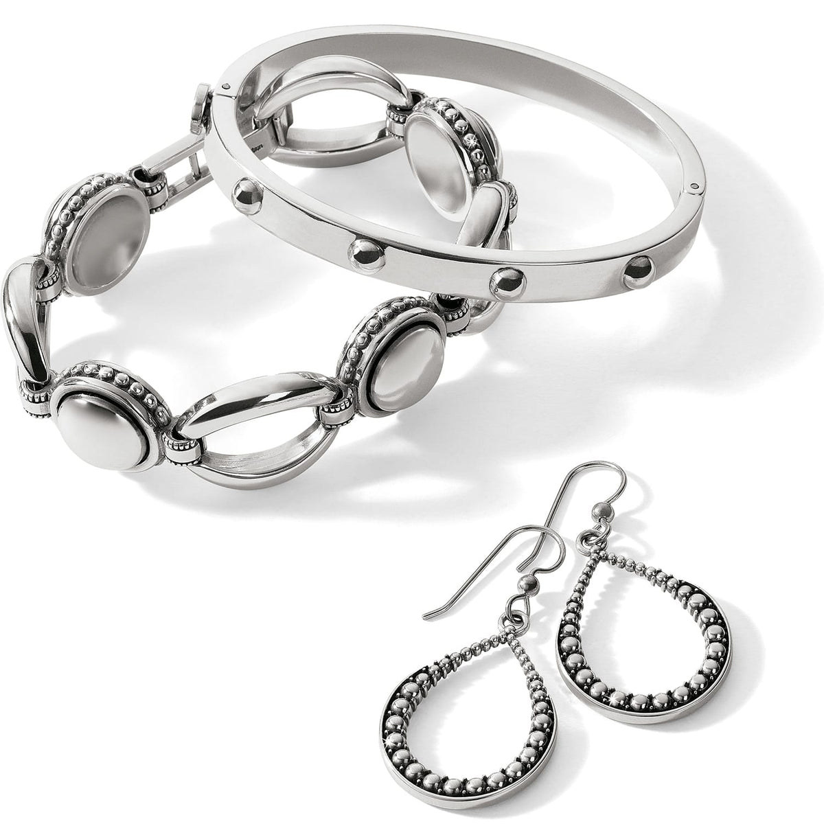 Brighton silver-plated jewelry set styled with linked bracelet, studded bangle, and beaded teardrop earrings on a white background