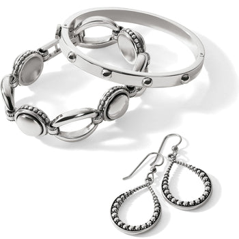Brighton silver-plated jewelry set styled with linked bracelet, studded bangle, and beaded teardrop earrings on a white background