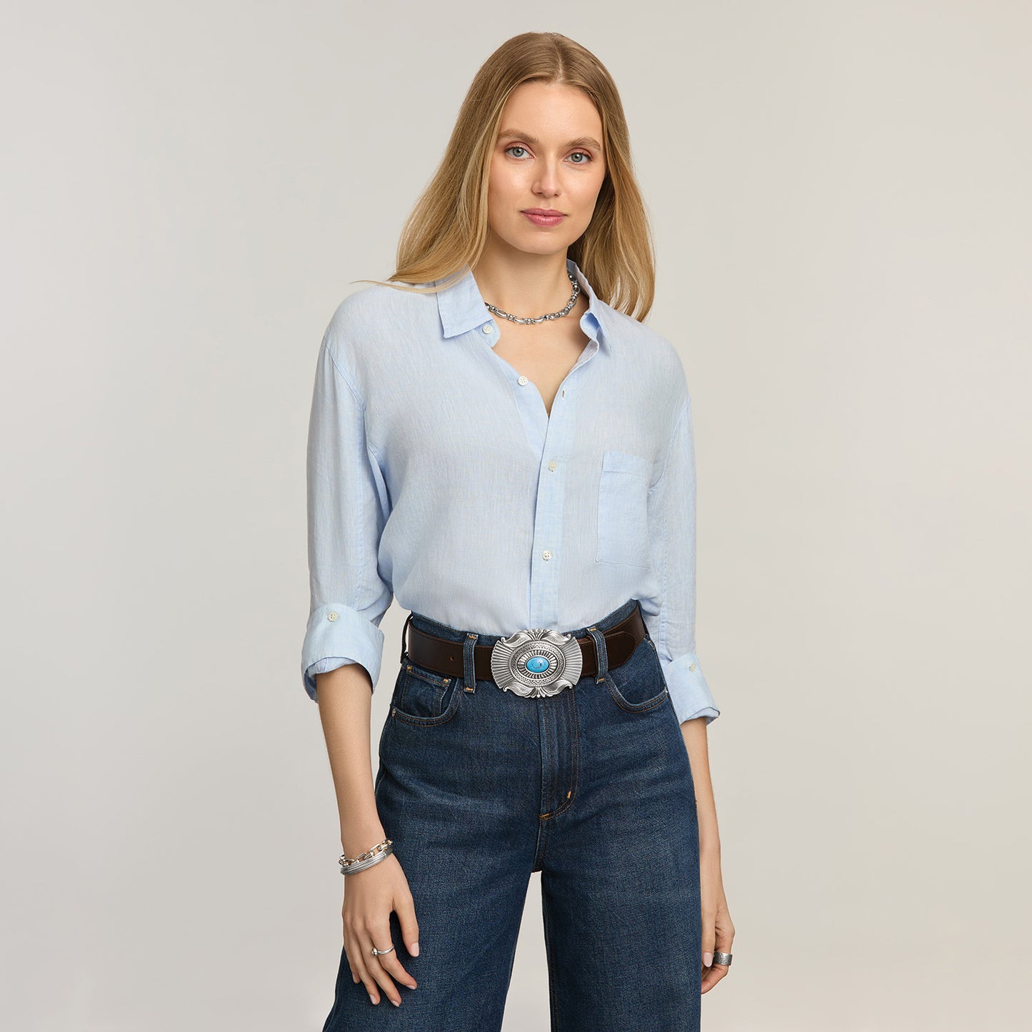 Model wearing a Brighton brown leather belt with oval silver-tone buckle featuring turquoise stone centerpiece