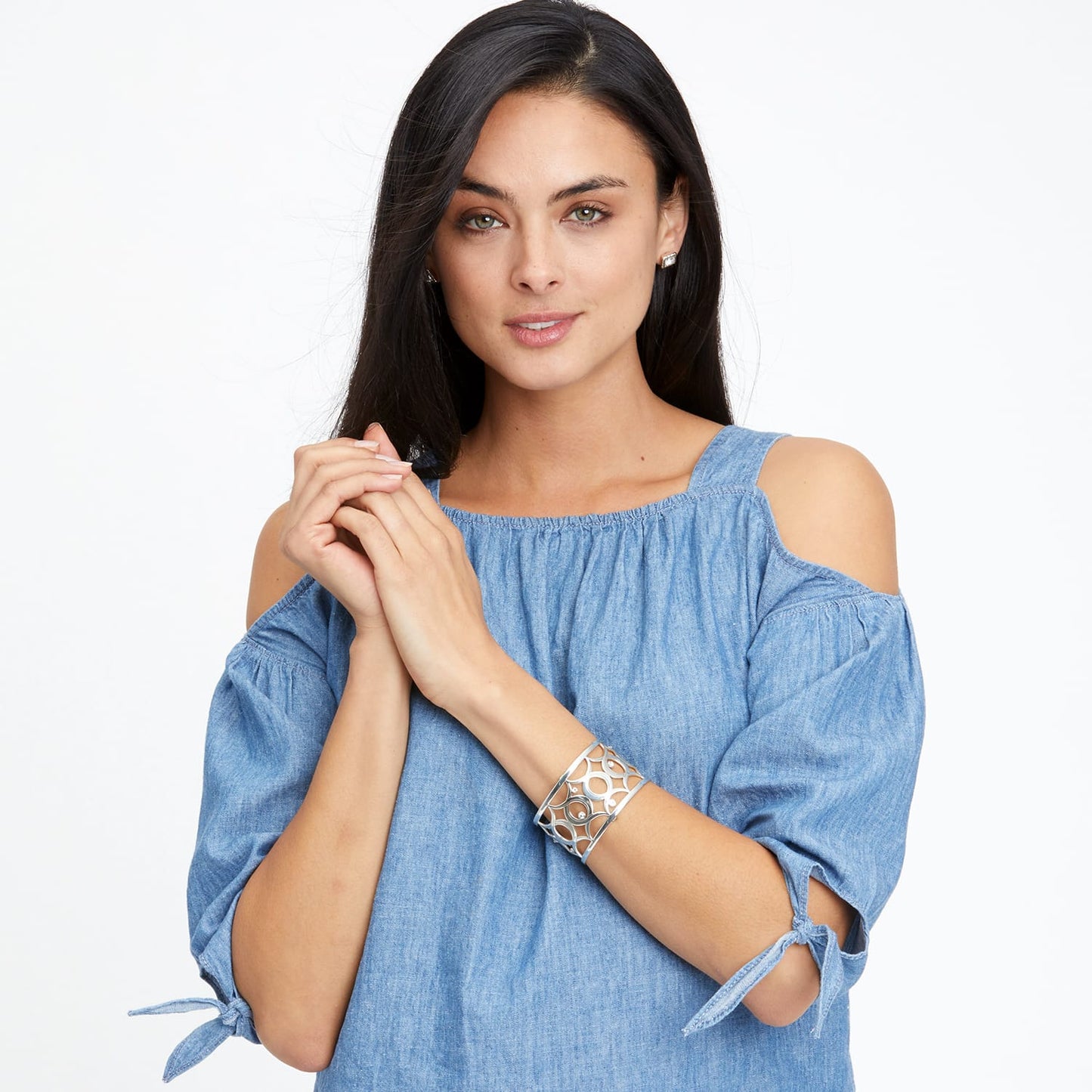 Model wearing a Brighton silver-plated cuff bracelet with openwork circular design paired with silver-tone crystal stud earrings