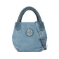 Brighton blue denim handbag with braided leather handles, silver-tone medallion accent, and adjustable strap on a white background
