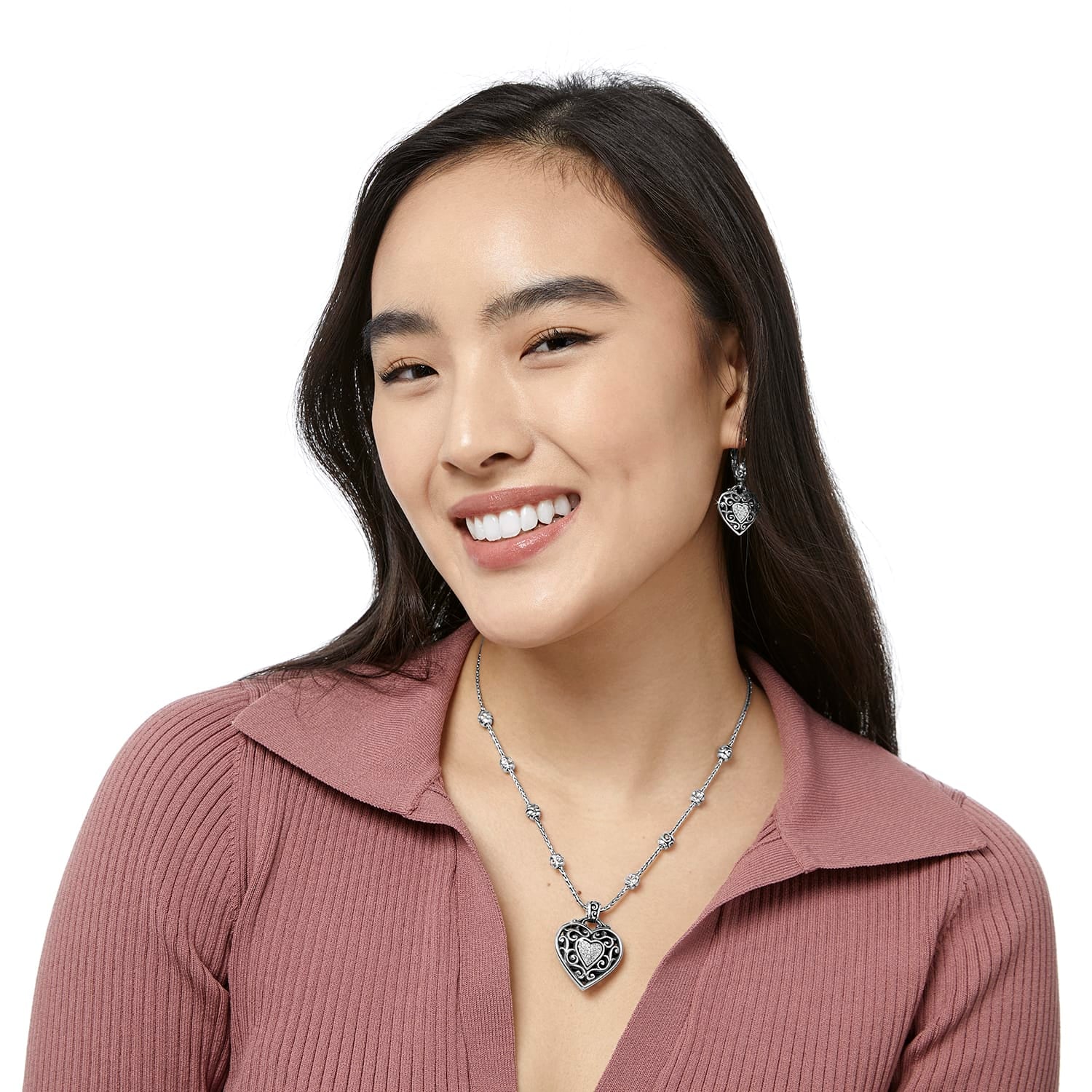 Model wearing a Brighton silver-plated heart pendant necklace with crystal accents paired with matching heart drop earrings