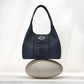 Brighton navy leather handbag with tonal scroll embroidery and silver-tone medallion, balanced on a stone on a white background