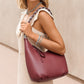 Model with a Brighton burgundy leather hobo handbag featuring a braided multicolor shoulder strap and silver-tone accents