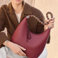 Brighton burgundy leather handbag with braided multicolor strap and silver-tone engraved hardware accents held by model