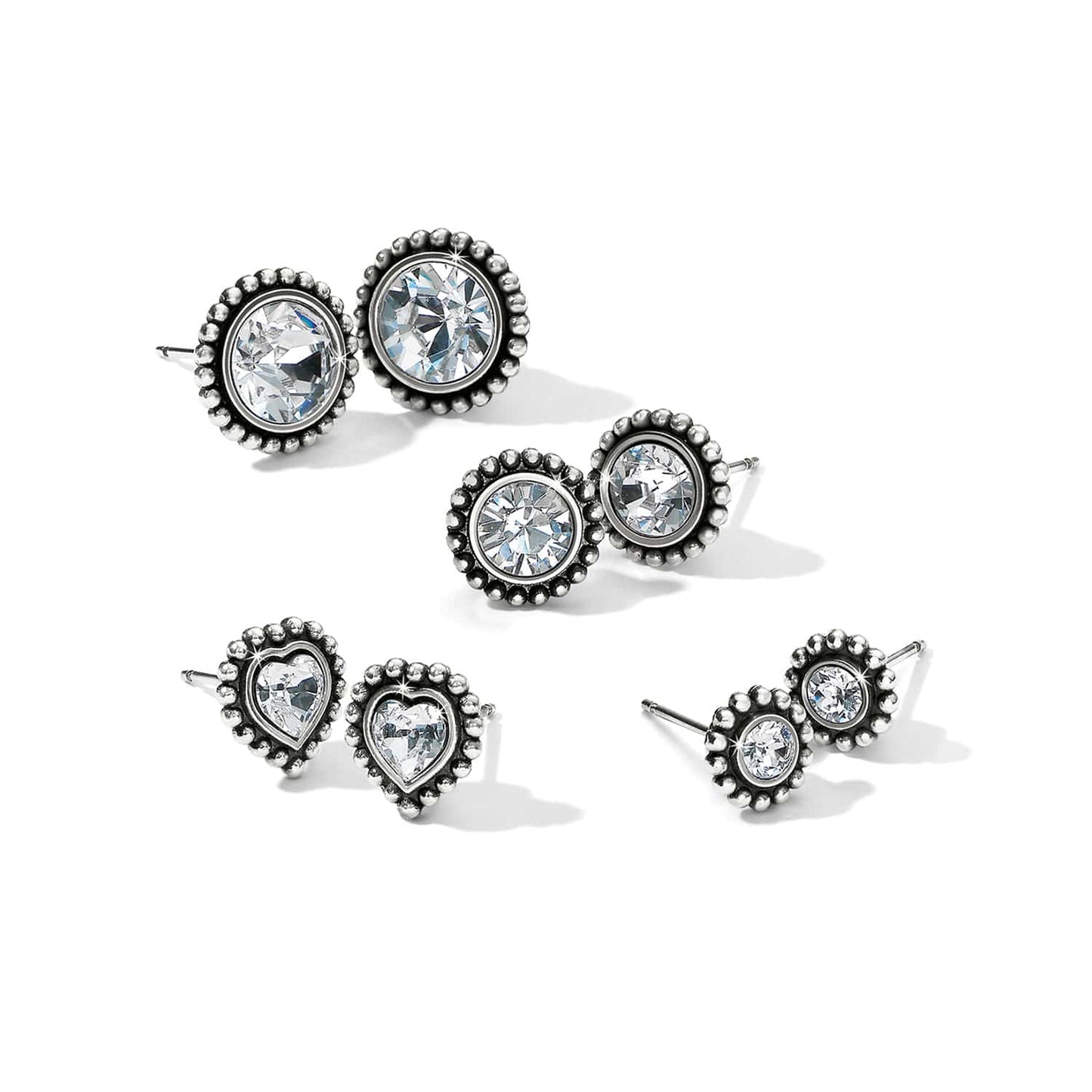 Brighton stud earrings set with crystals in silver-plated beaded frames in round and heart shapes on a white background