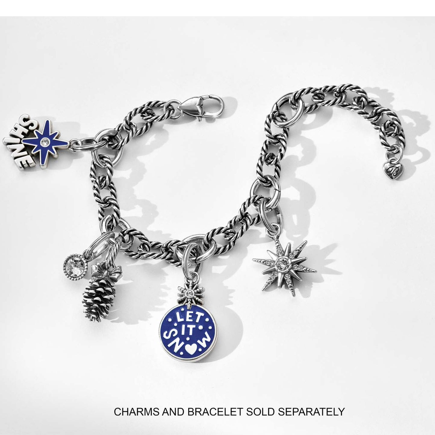 Brighton silver-plated charm bracelet with pinecone, snowflake, star, crystal, and blue Let It Snow charms on a white background