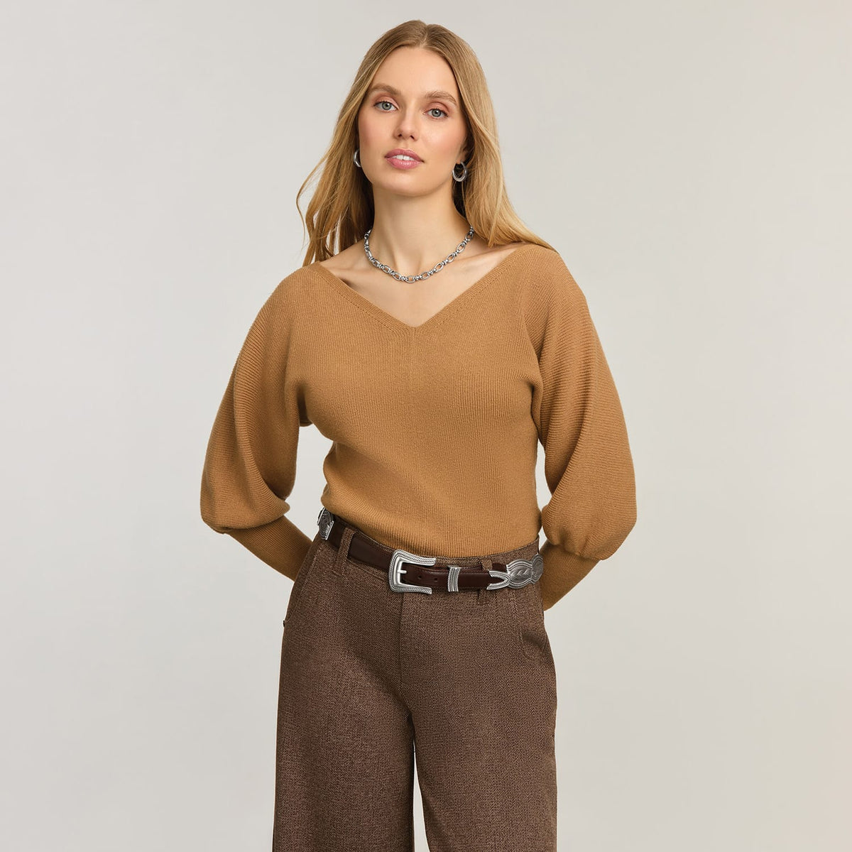 Model wearing a Brighton brown leather belt with ornate silver-tone buckle and keeper details on wide-leg trousers