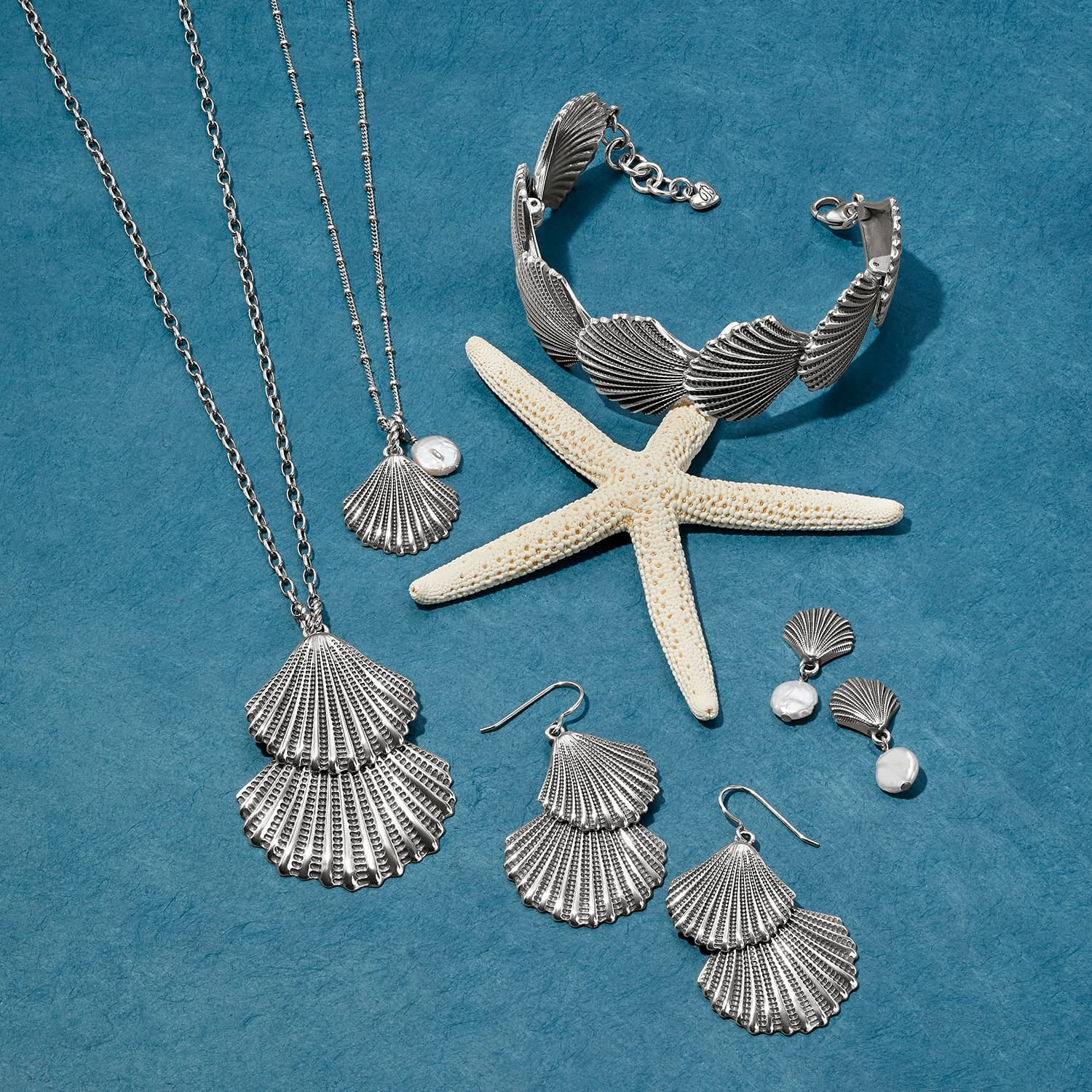 Brighton silver-plated shell jewelry set styled with a starfish and pearl accents on a blue background
