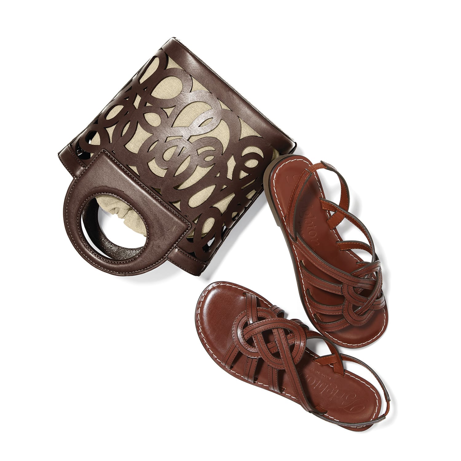 Brighton brown leather handbag with cutout scroll design styled with coordinating brown leather strappy sandals on white